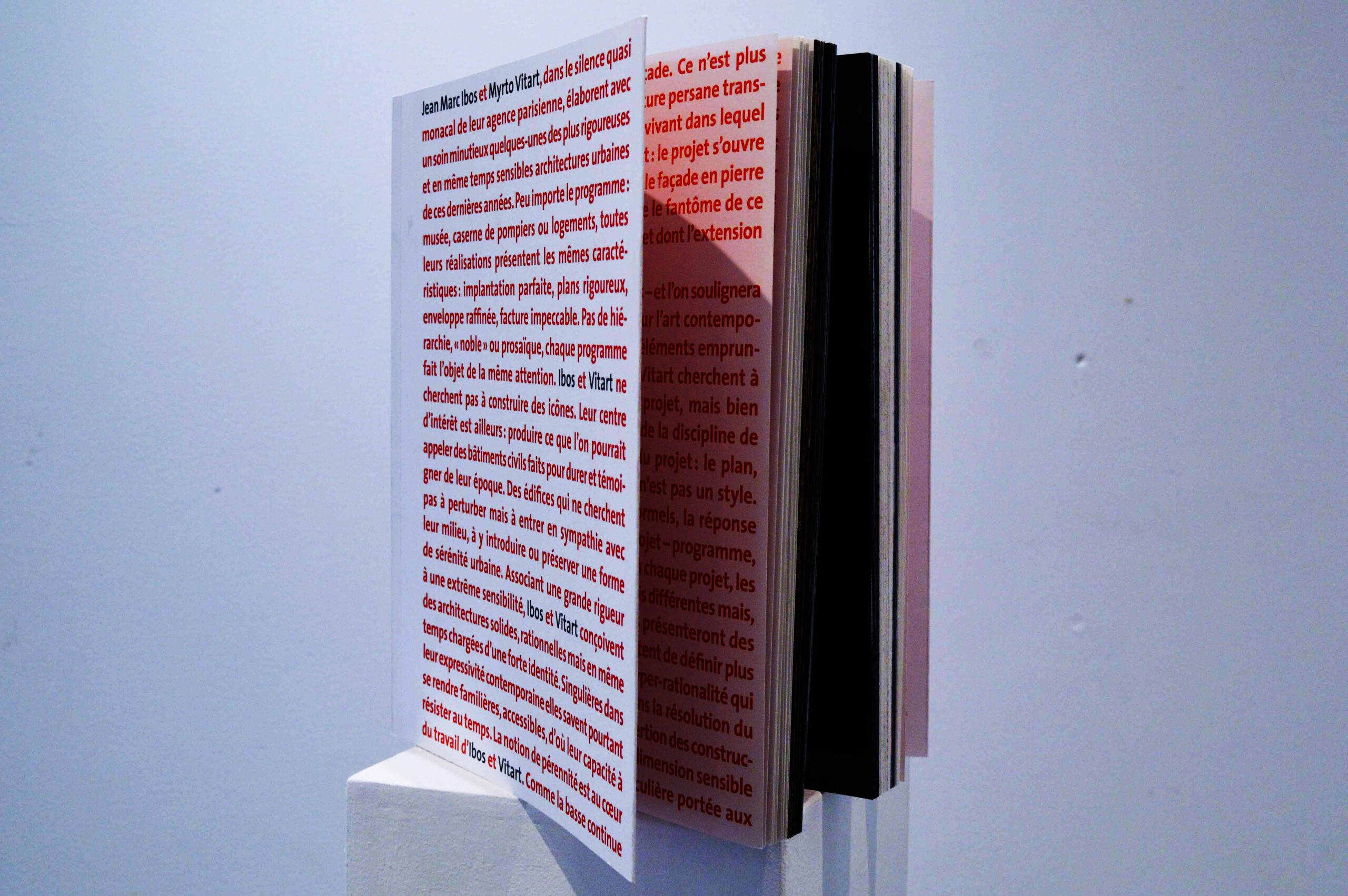 Livre dressé ouvert sur un texte rouge.