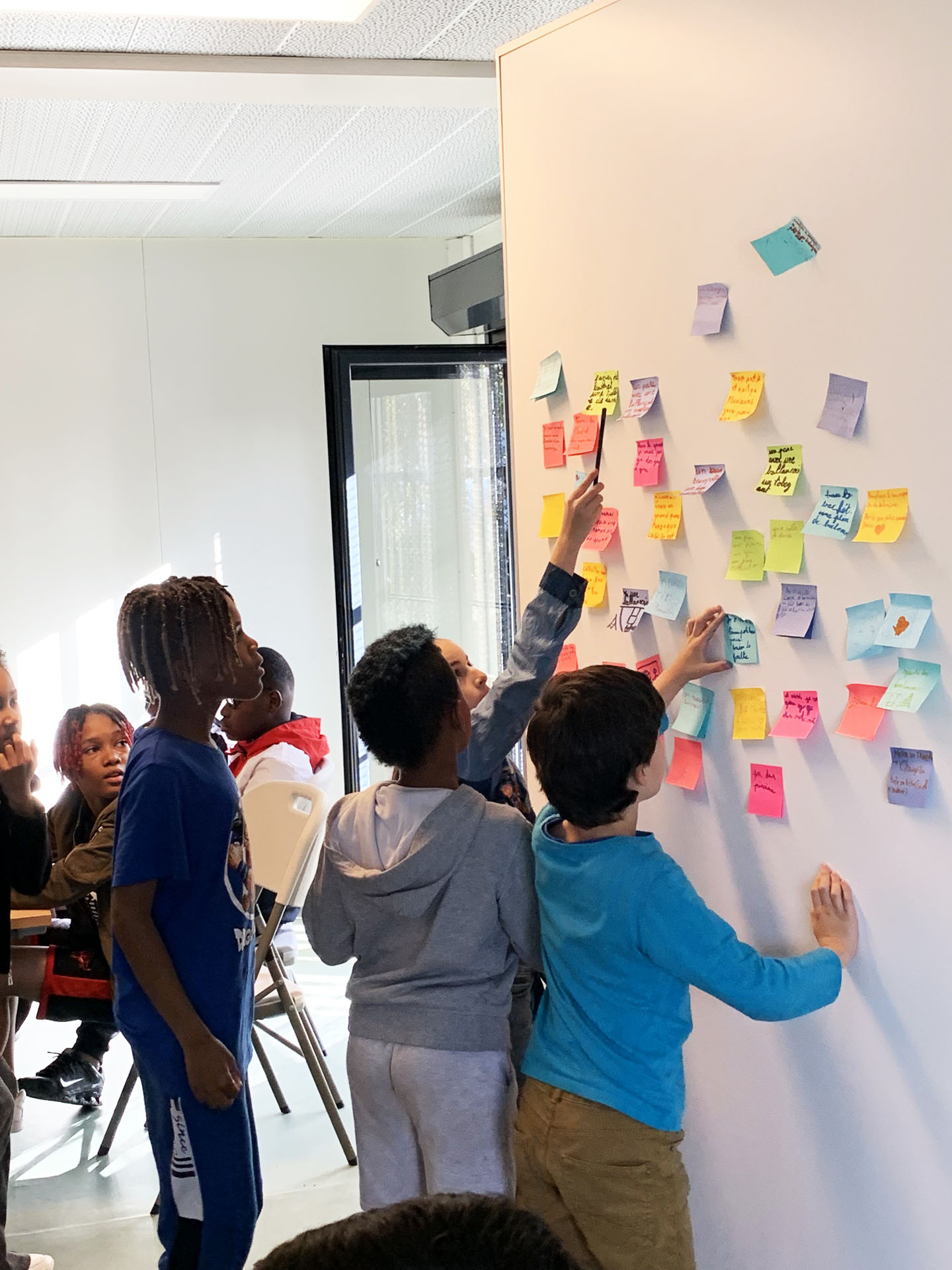Enfants devant des notes sur un mur.