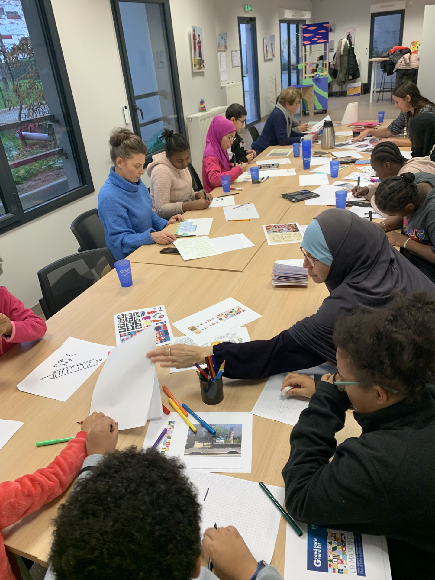 Groupe autour de tables et de dessins.