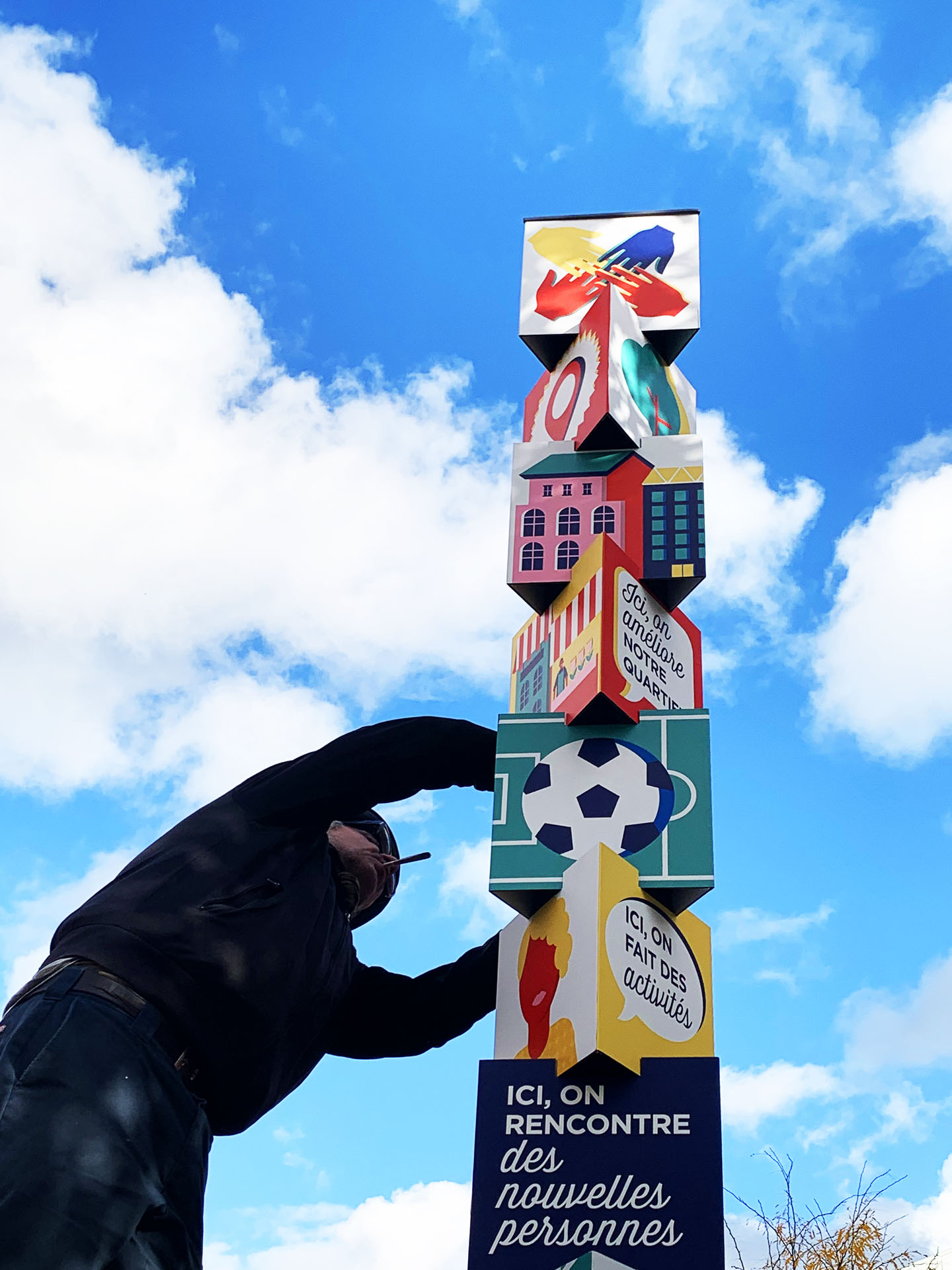 Totem illustré avec une main au premier plan.