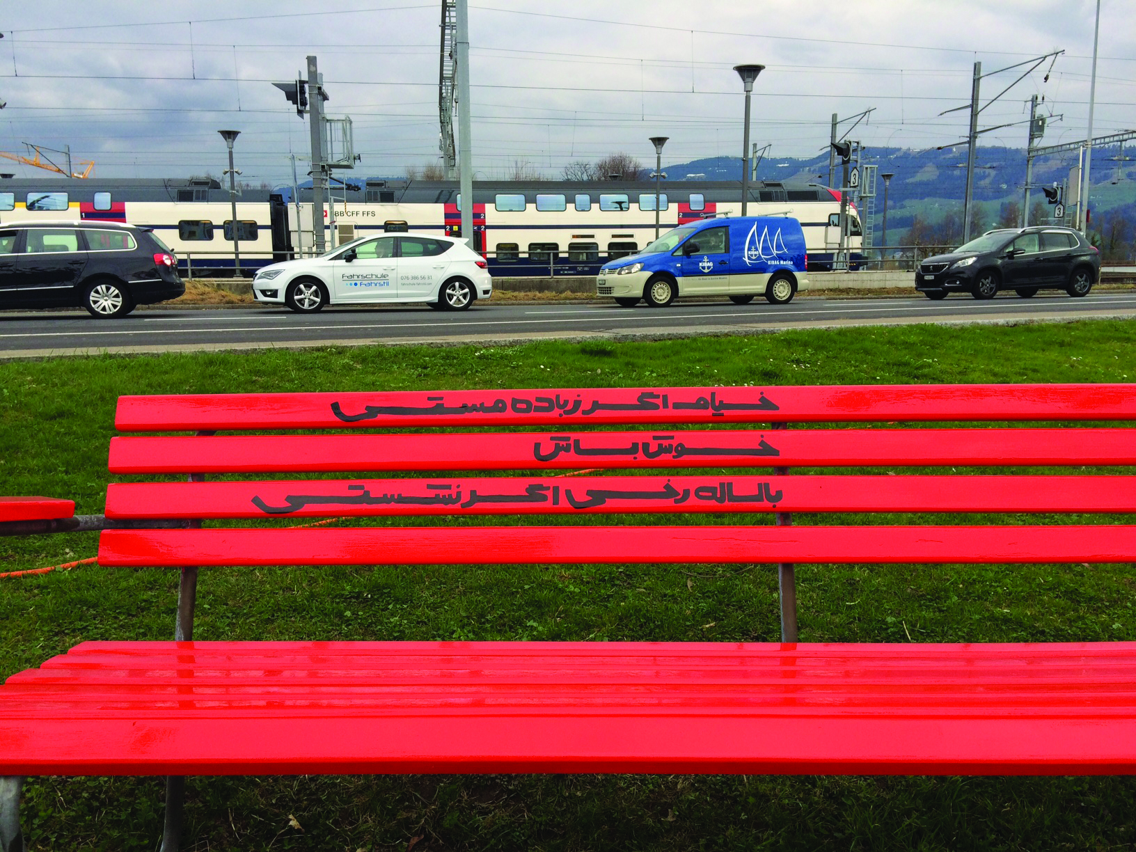 Red bench in front of a railway.