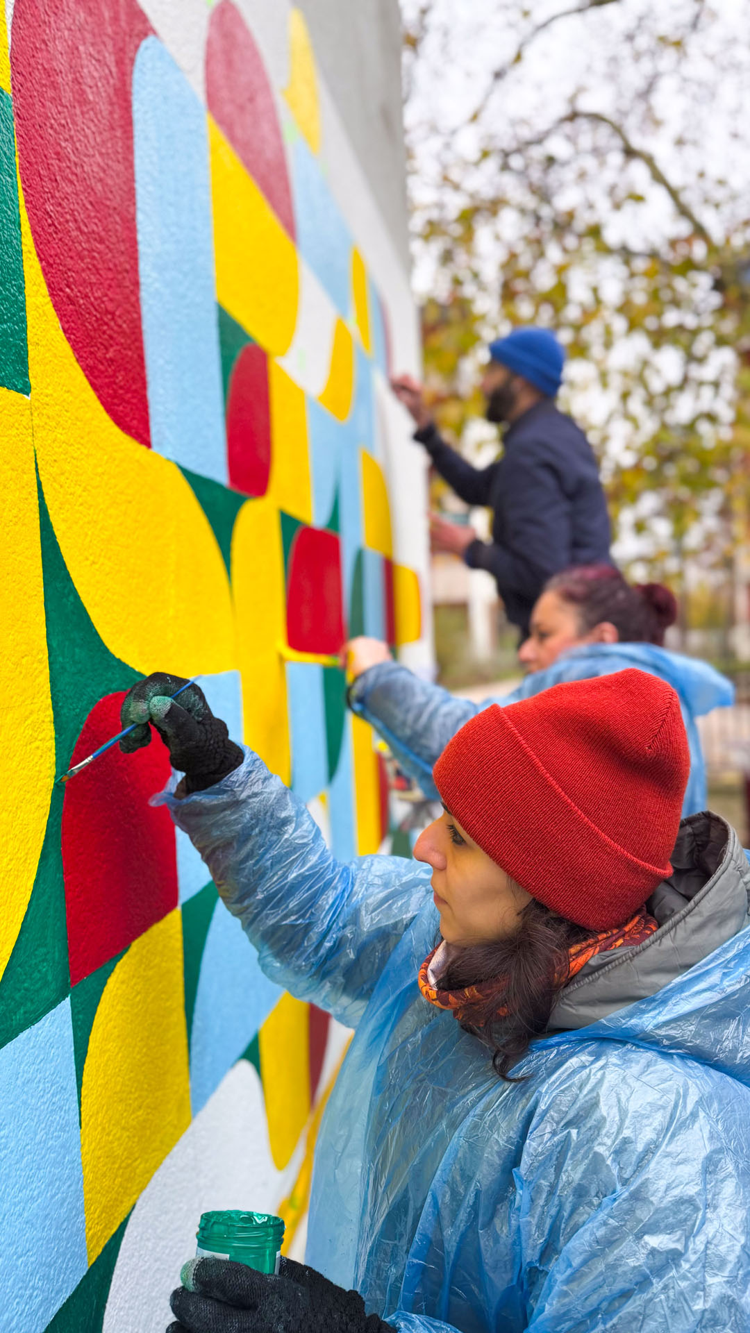 Personne au chapeau rouge devant une fresque.