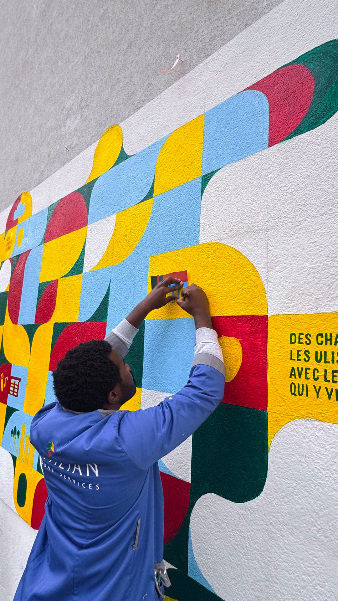 Personne en manteau bleu devant une fresque.