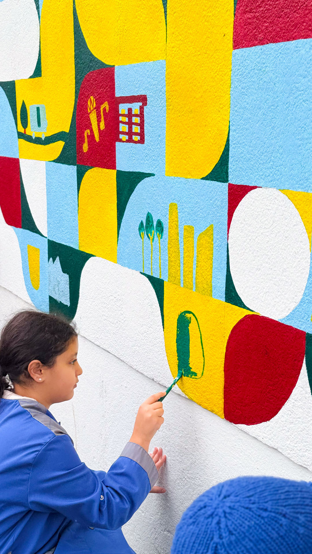 Enfant avec un rouleau devant un mur.