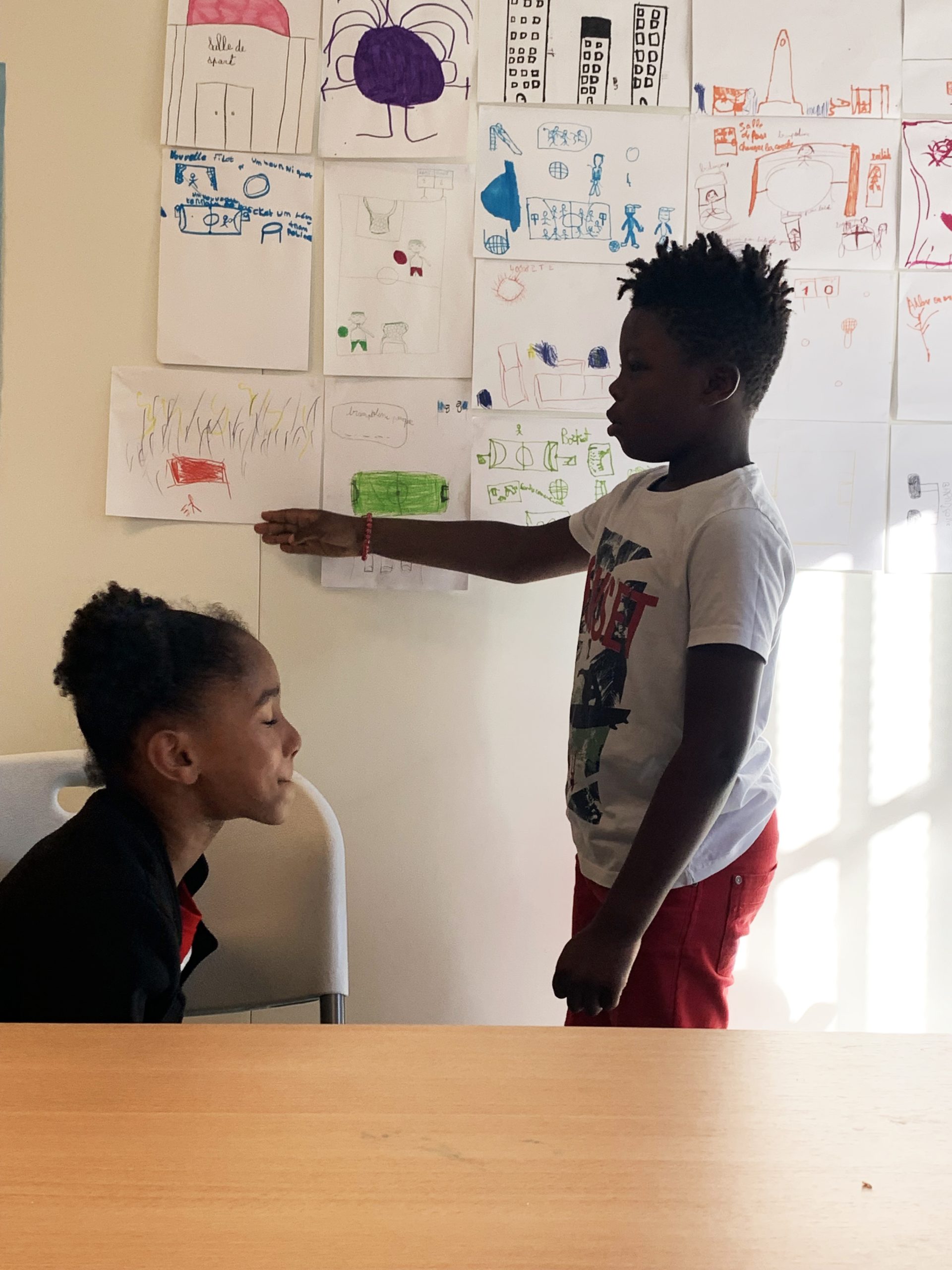 Enfants devant des dessins au mur.